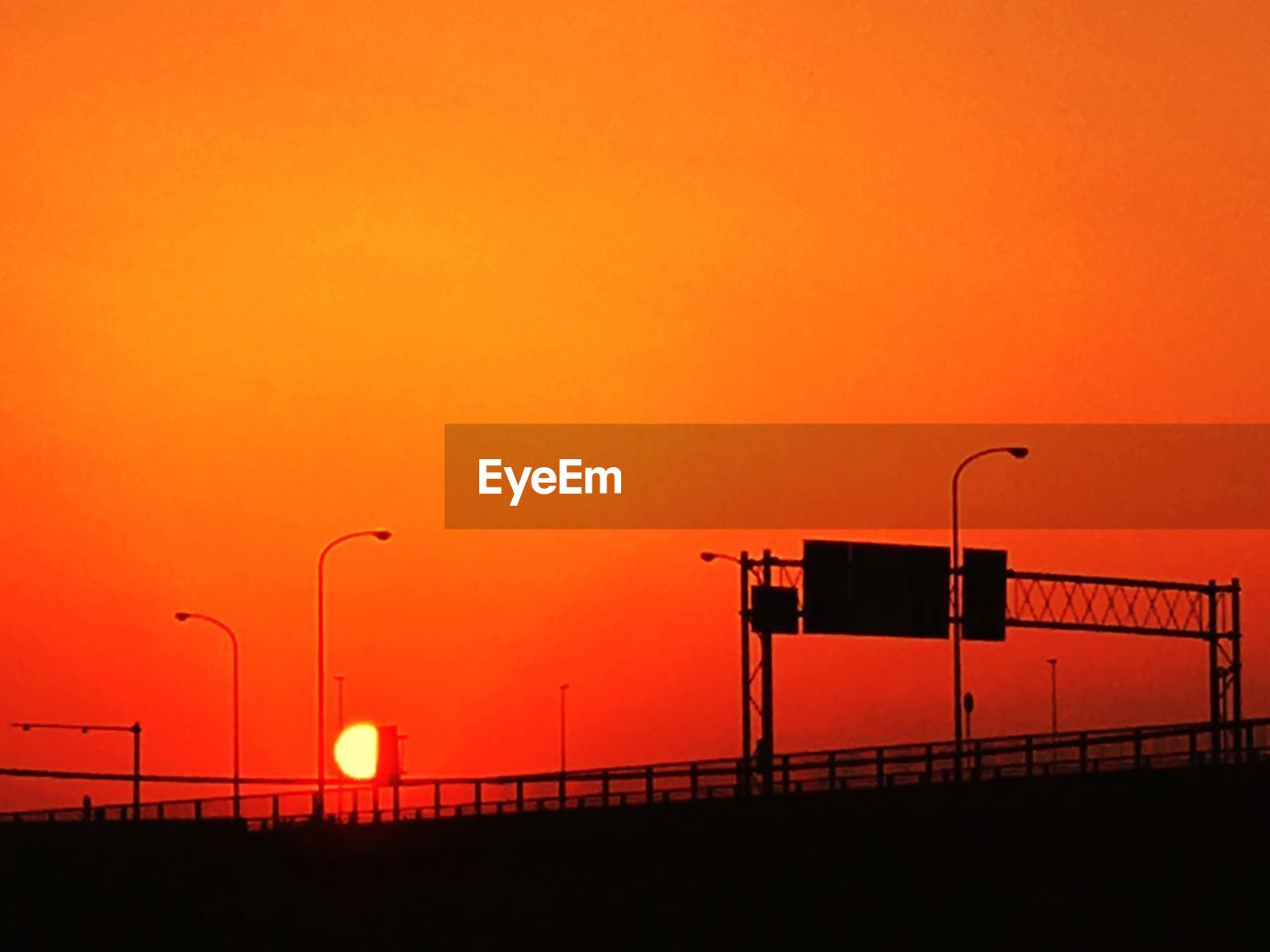 Silhouette street light against orange sky