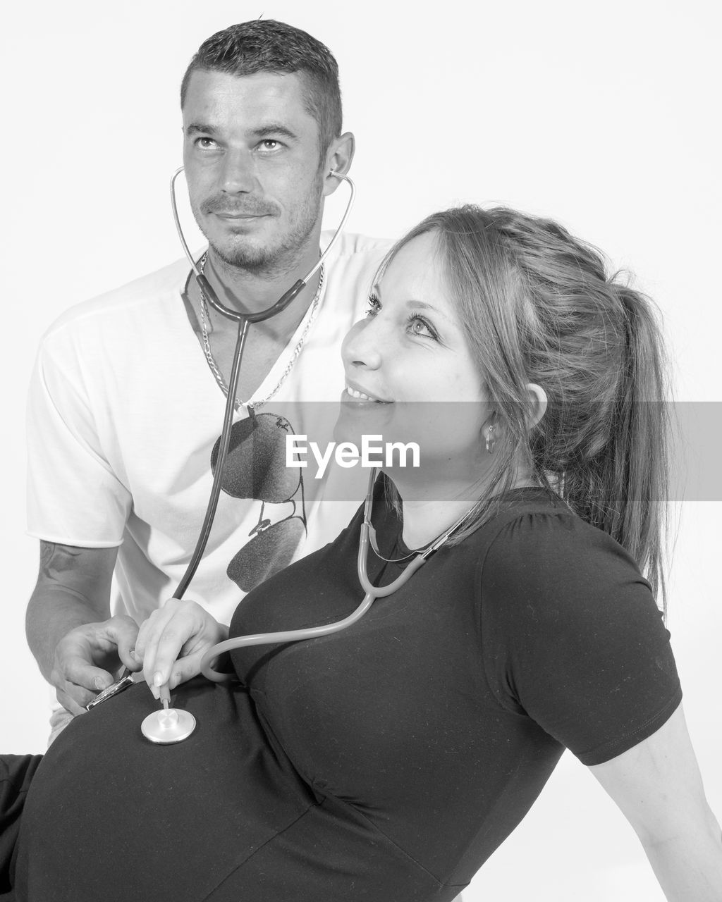 Expectant couple looking away against white background