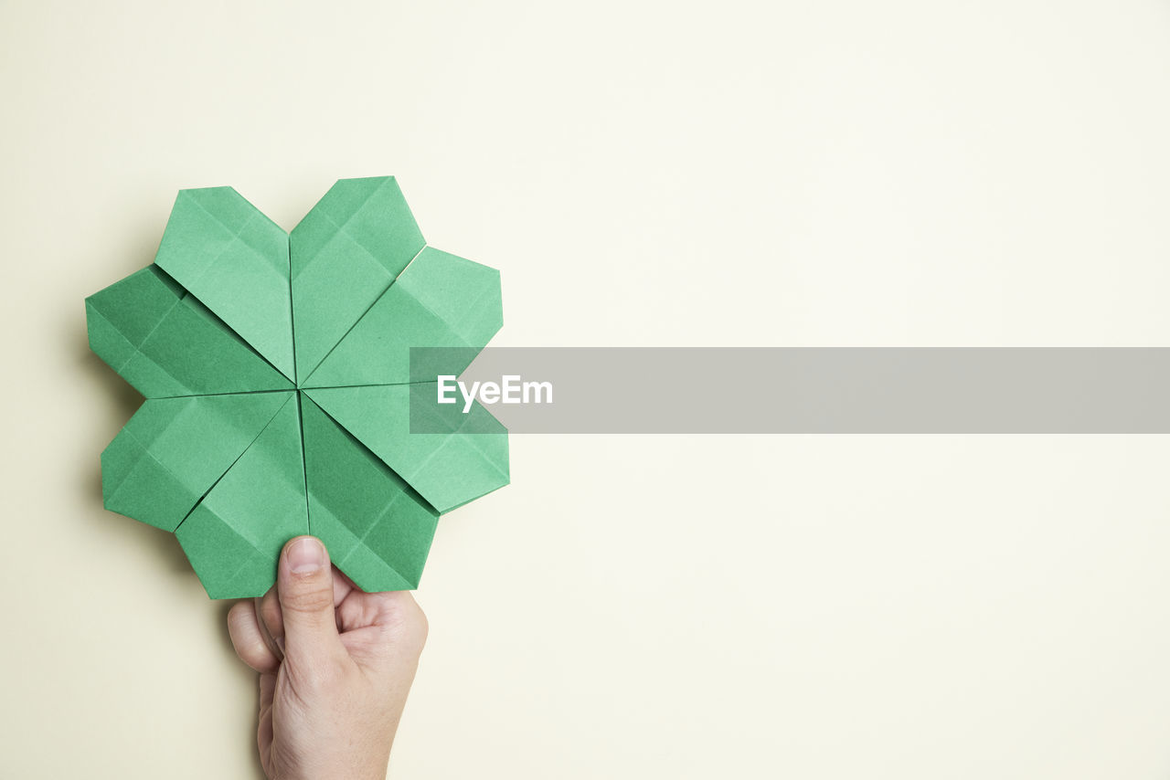 CROPPED IMAGE OF PERSON HOLDING PAPER AGAINST WHITE BACKGROUND