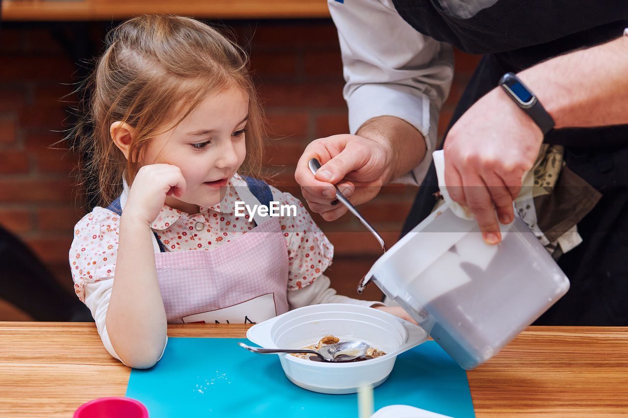 Midsection of man serving food to girl on table