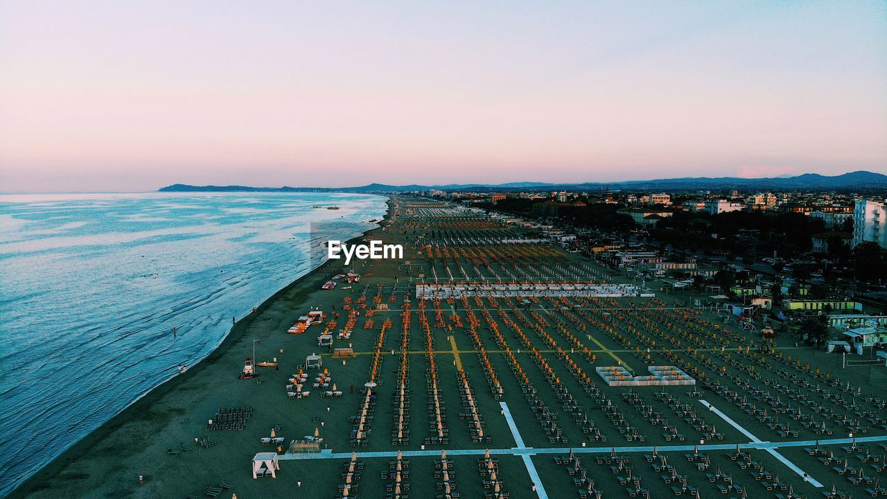 High angle view of city by sea against sky during sunset