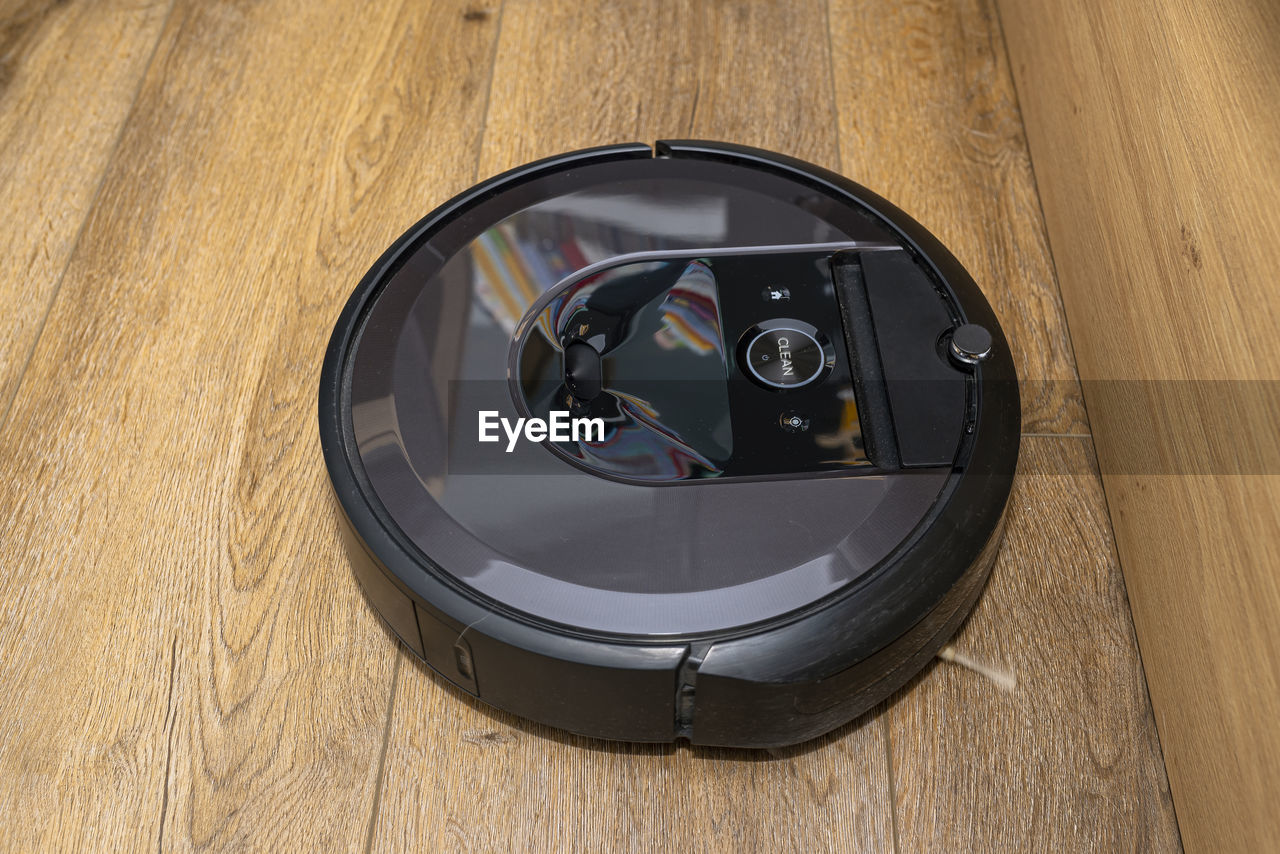 A modern robotic vacuum cleaner running on vinyl panels, an autonomous cleaning robot.