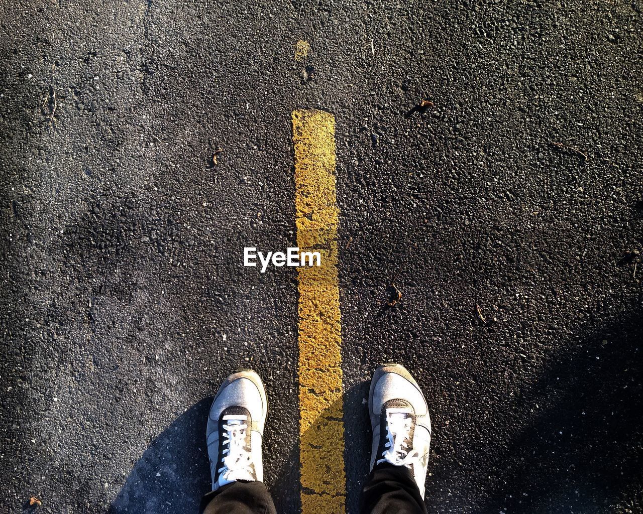 Low section of man standing on road marking