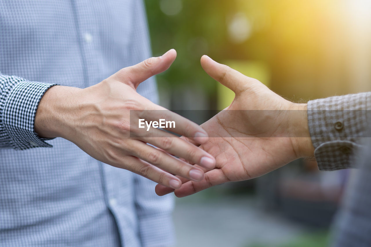 Midsection of man shaking hand with friend