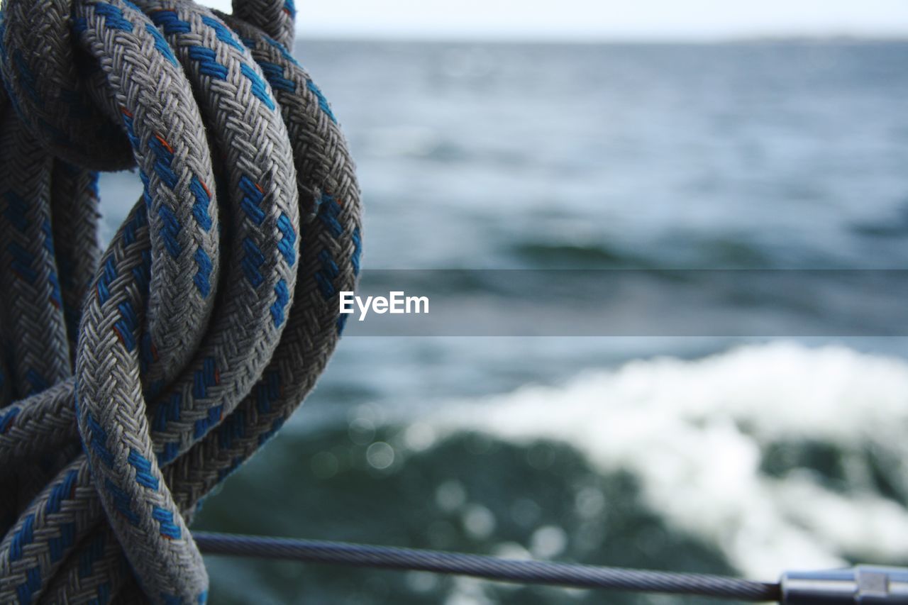 Close-up of rope tied to railing against sea