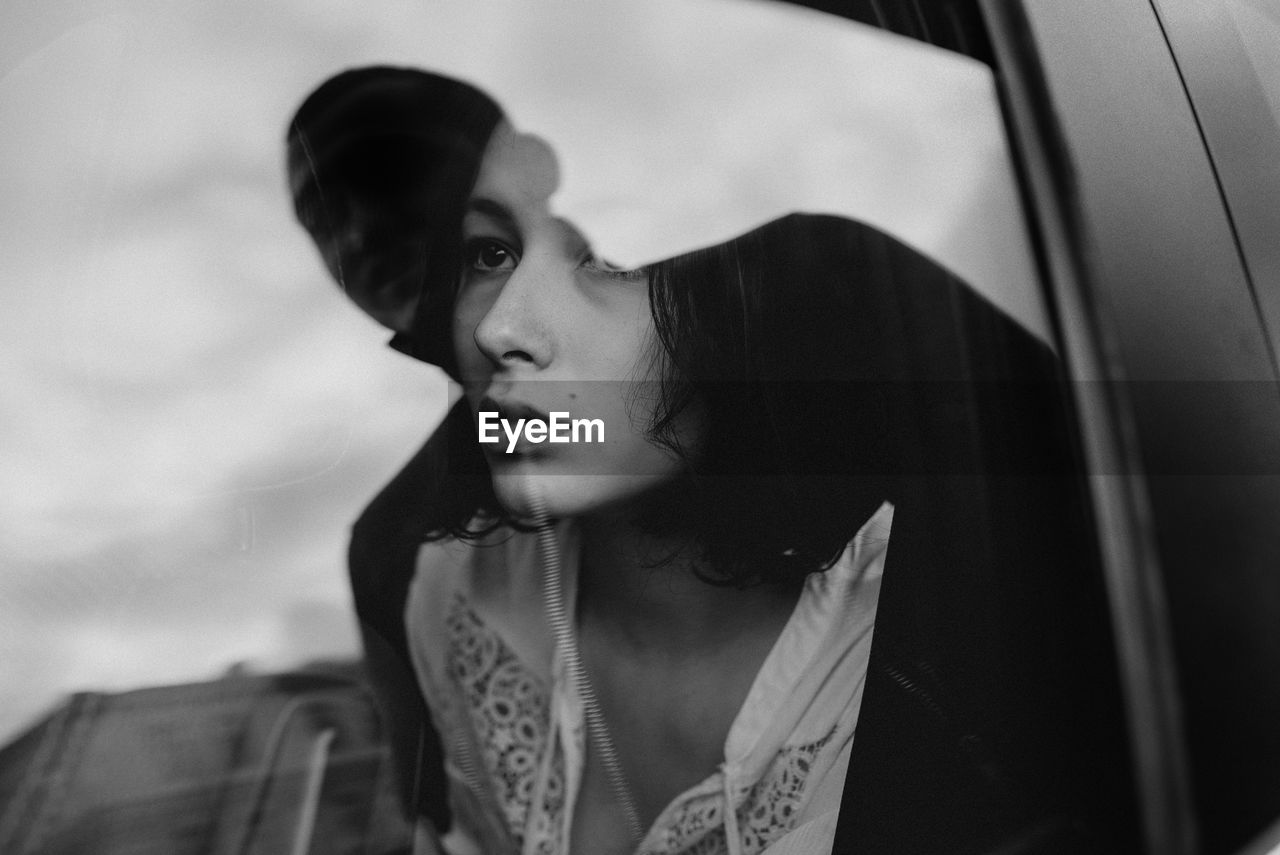 PORTRAIT OF YOUNG WOMAN LOOKING DOWN WHILE SITTING IN CAR