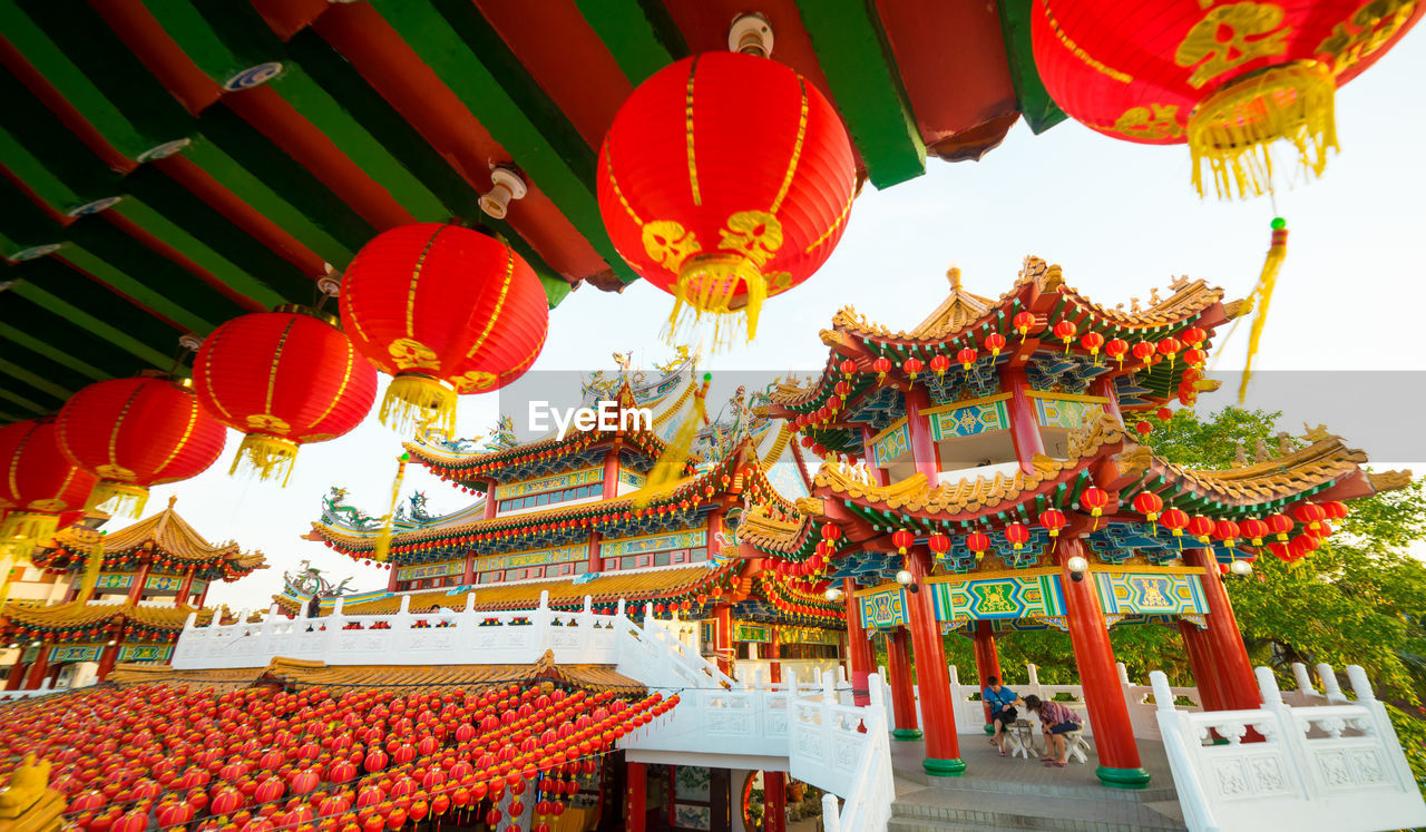 LOW ANGLE VIEW OF LANTERNS HANGING OUTSIDE TEMPLE AGAINST BUILDING