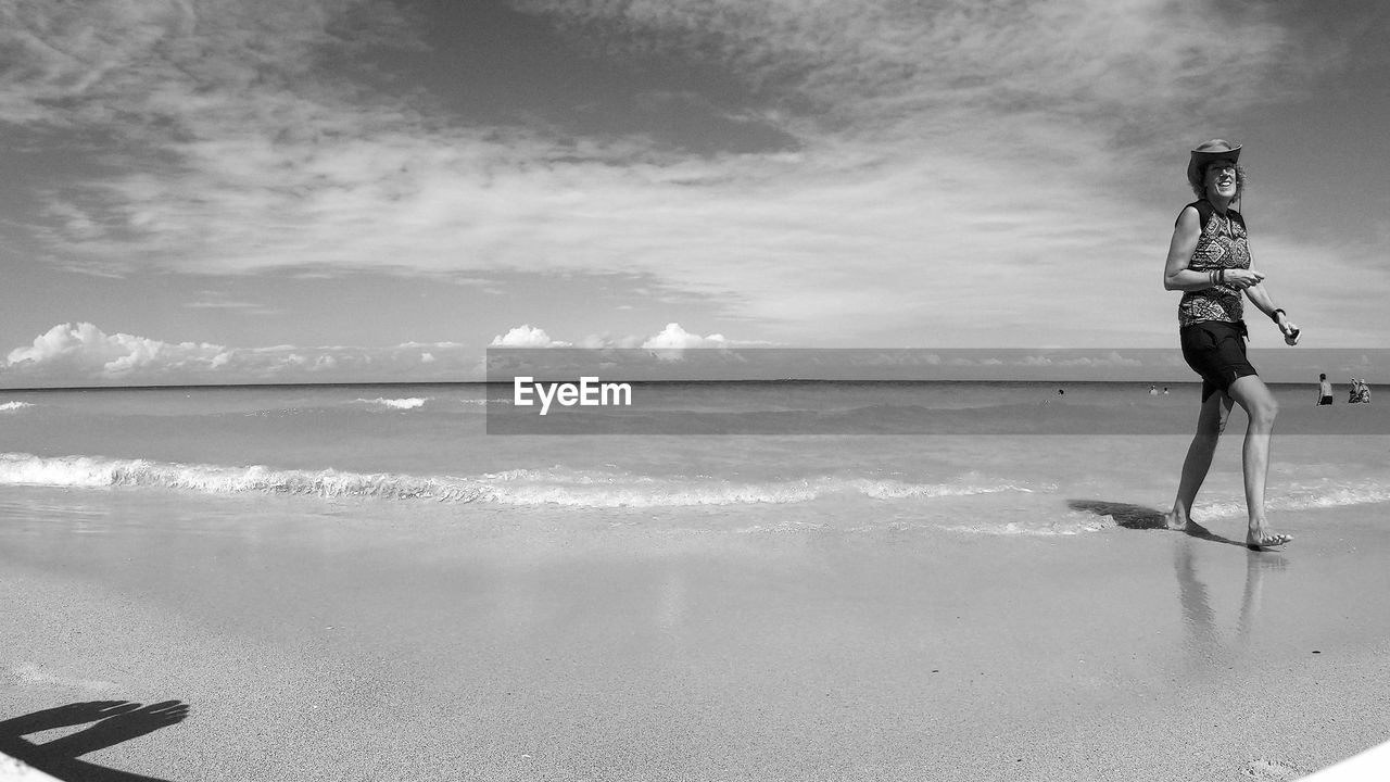 FULL LENGTH OF MAN STANDING ON BEACH AGAINST SKY