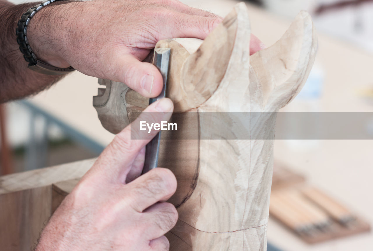 Cropped hands of man carving wood