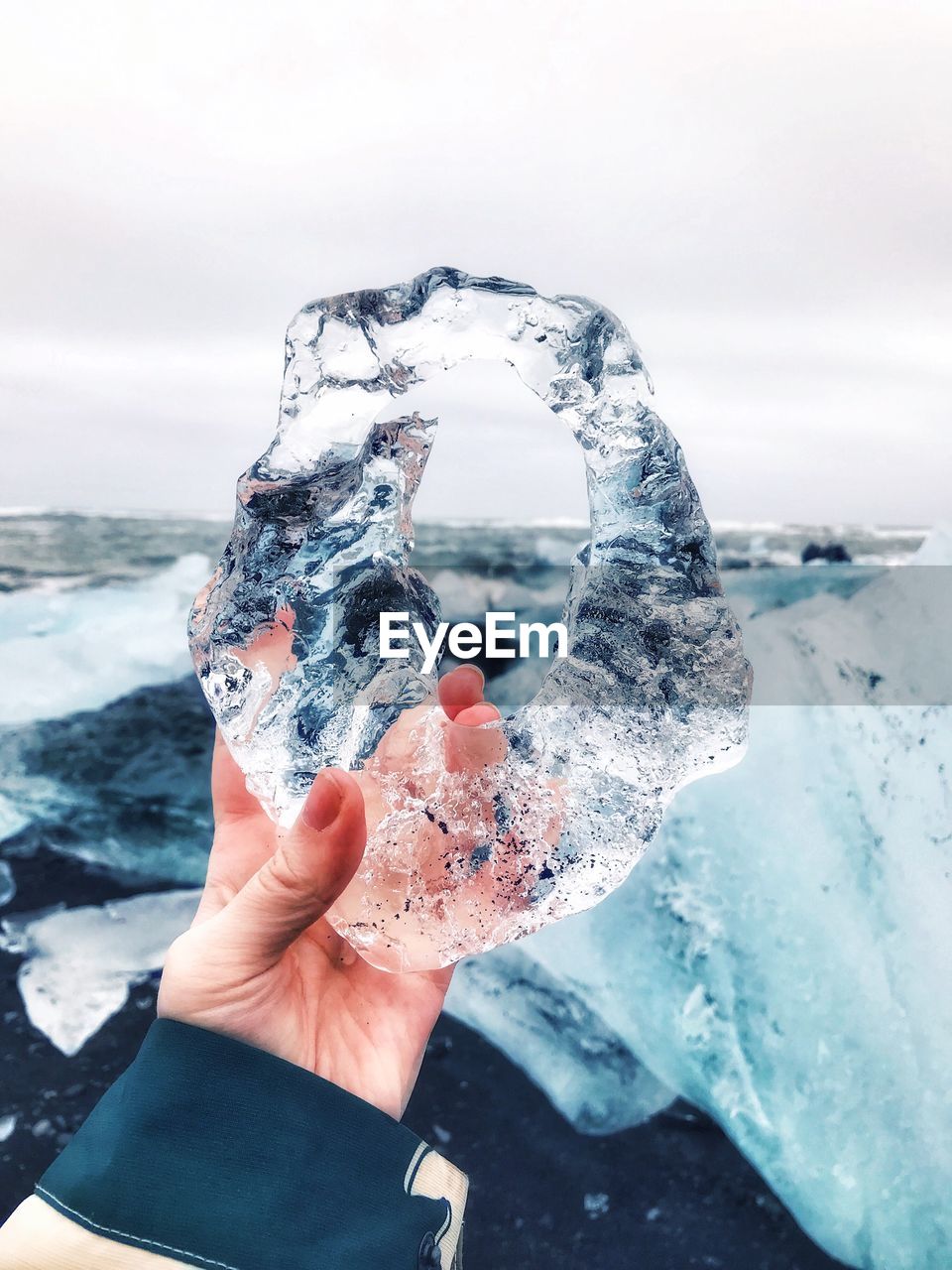 Close-up of person holding ice against sky