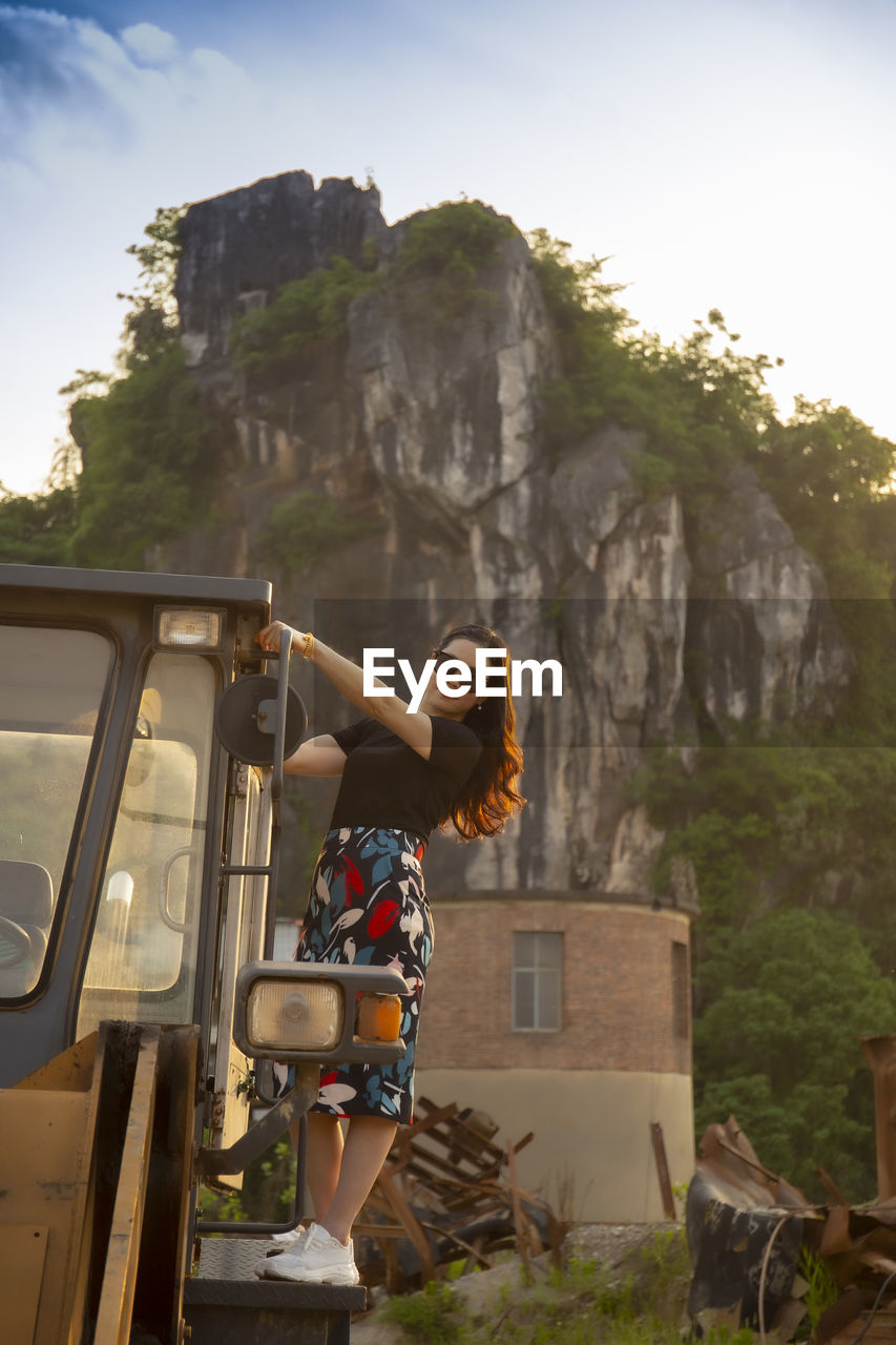 Side view of woman with arms outstretched against mountain