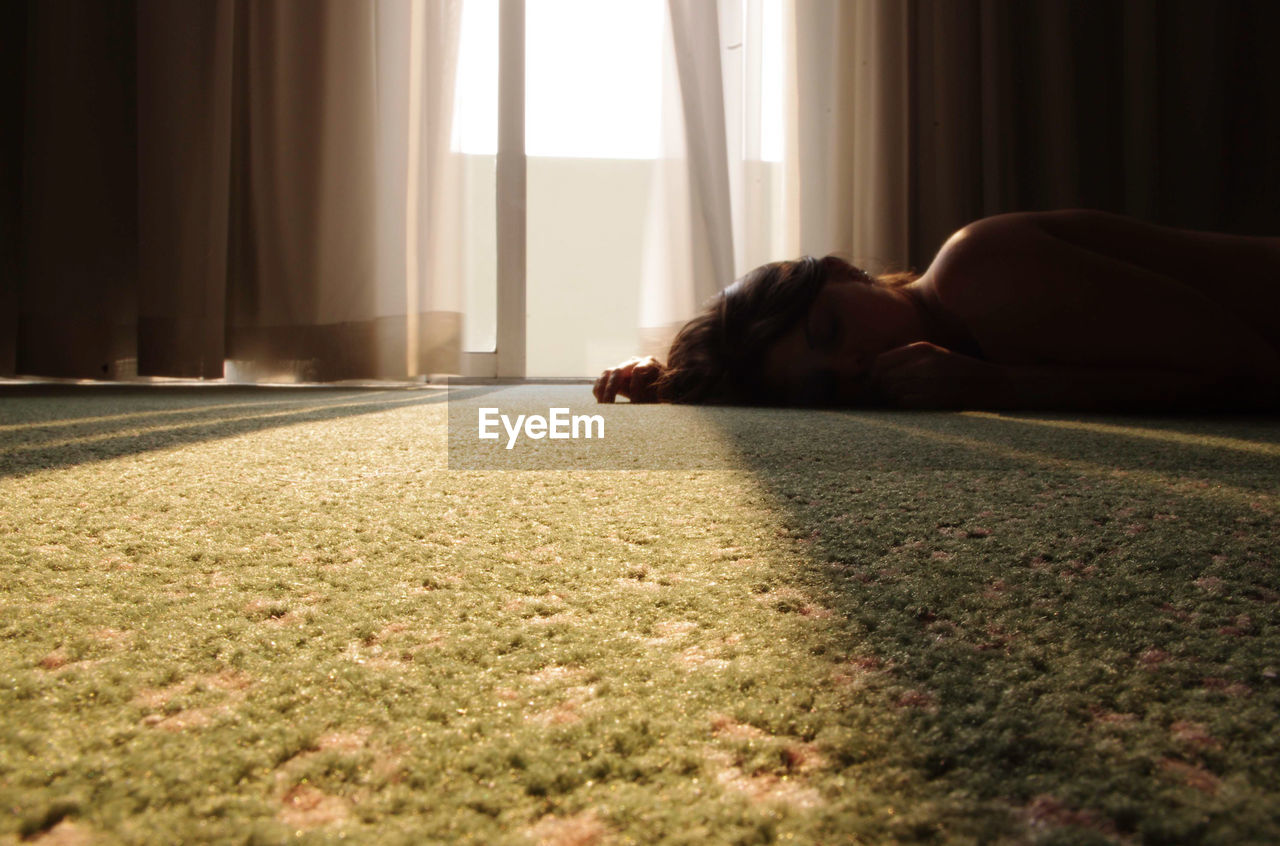 Naked woman lying on rug at home