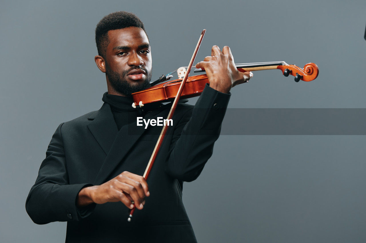 midsection of man playing violin while standing against white background