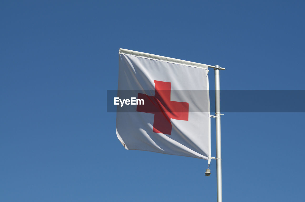 The flag of international red cross and red crescent movement against a blue sky in switzerland