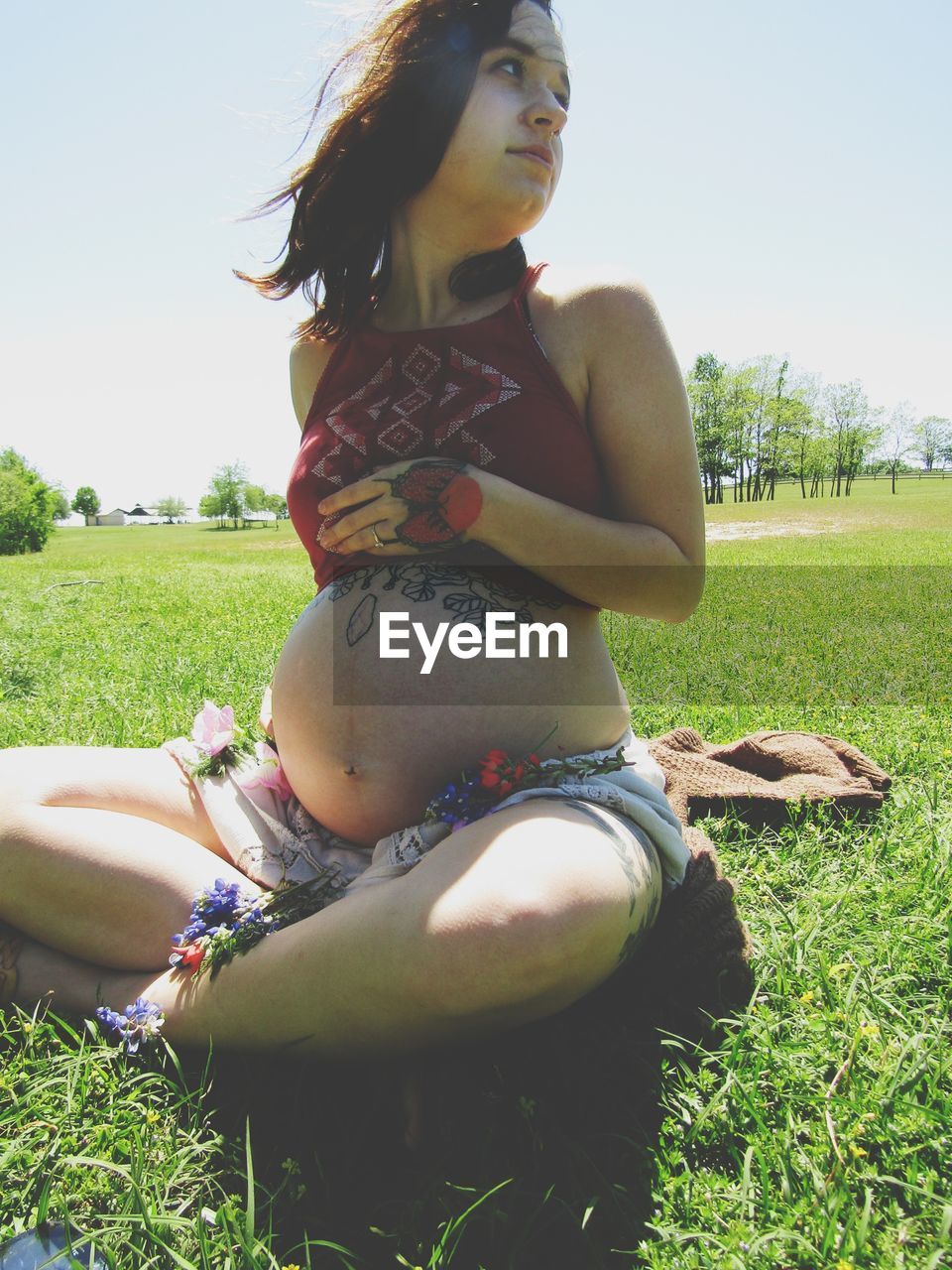 WOMAN SITTING ON GRASSY FIELD