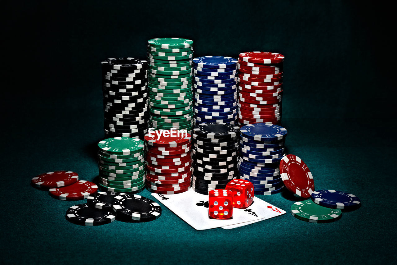 Stack of multi colored gambling chips on table against black background