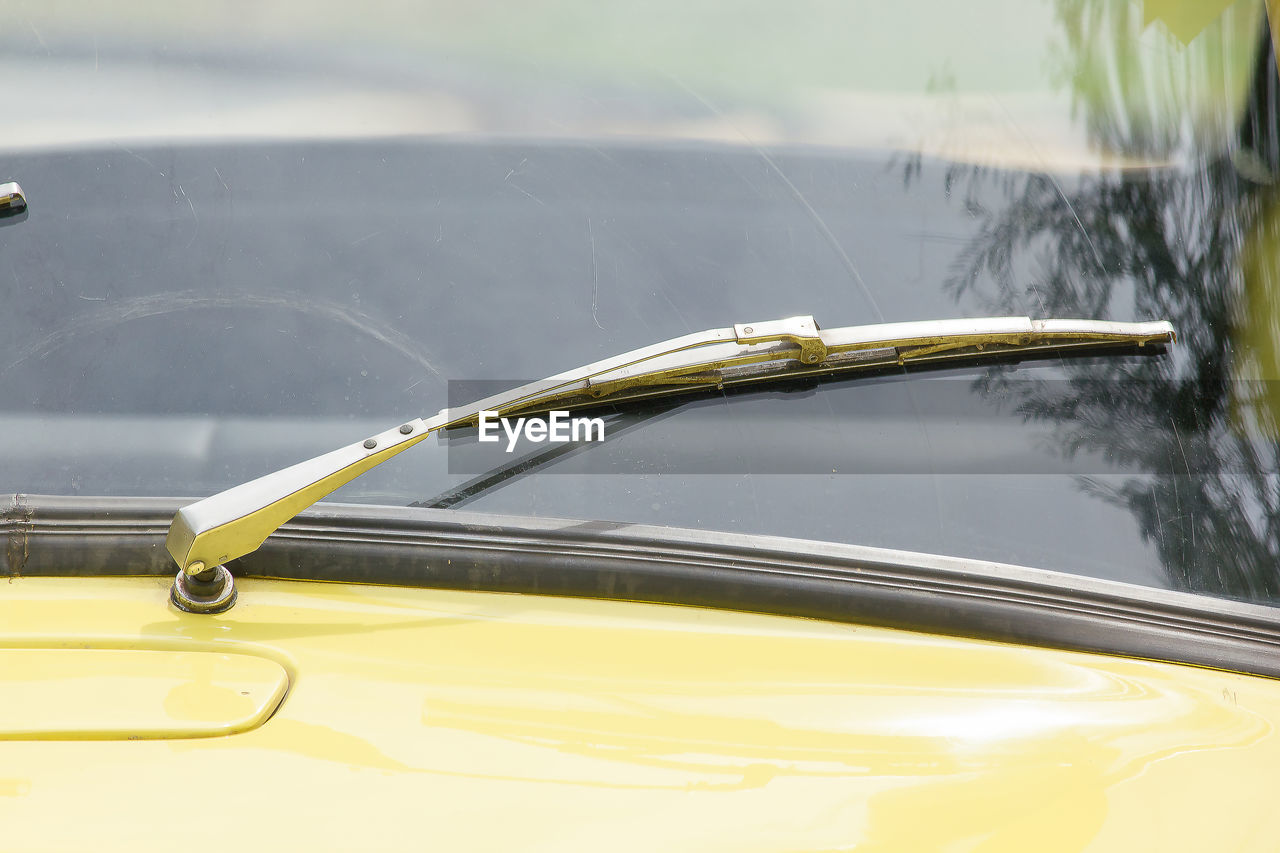 CLOSE-UP OF YELLOW CAR ON METAL MIRROR