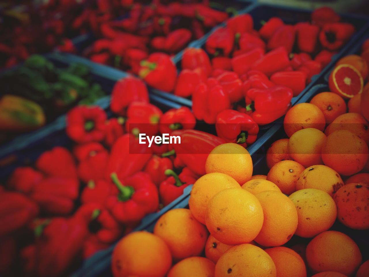 Oranges and bell peppers in crates at market for sale