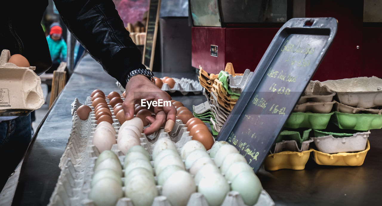 Midsection of man holding eggs for sale at market stall