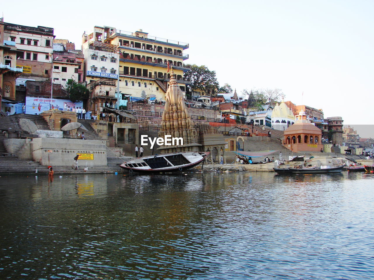 Sailboats moored on harbor by buildings against clear sky