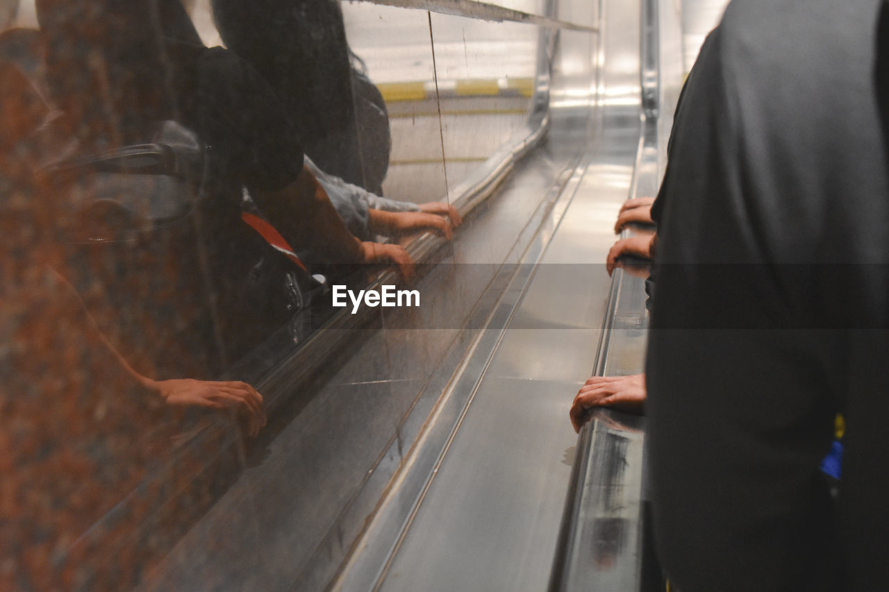 Midsection of man standing on escalator