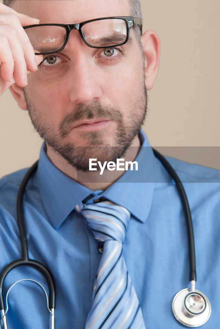 Close-up portrait of serious male doctor removing eyeglasses
