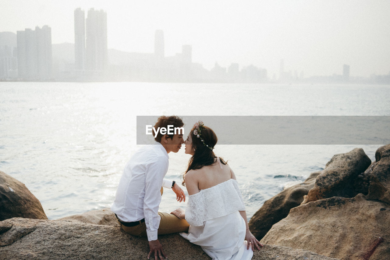 Couple sitting by sea on rocks