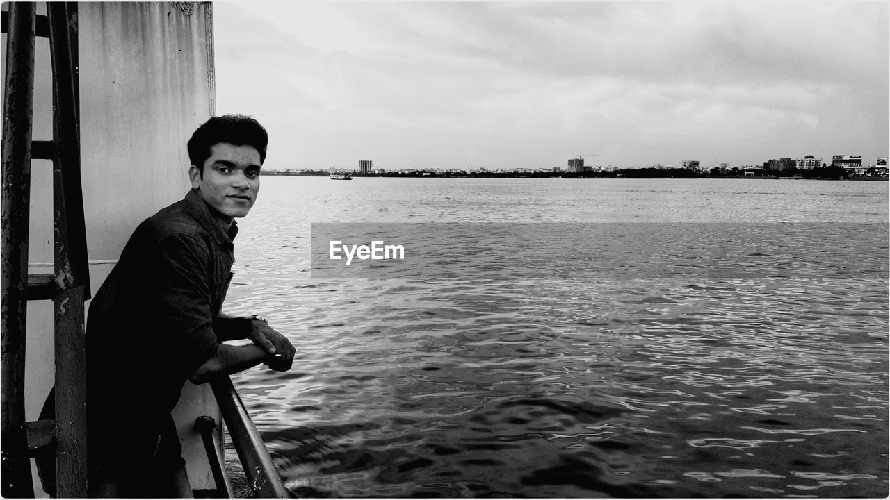 Portrait of young man standing on boat in sea