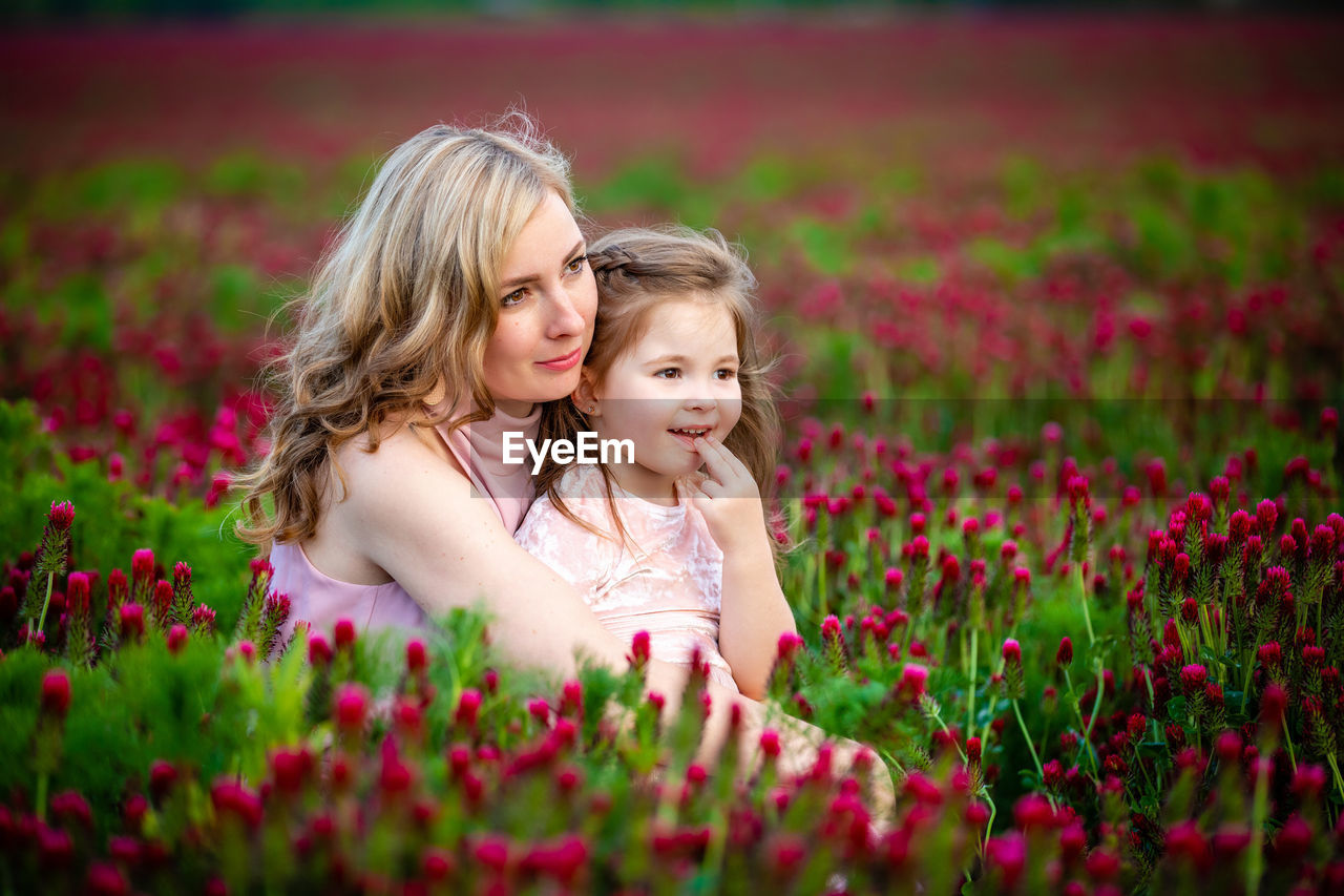 Mother and daughter amidst pink flowers