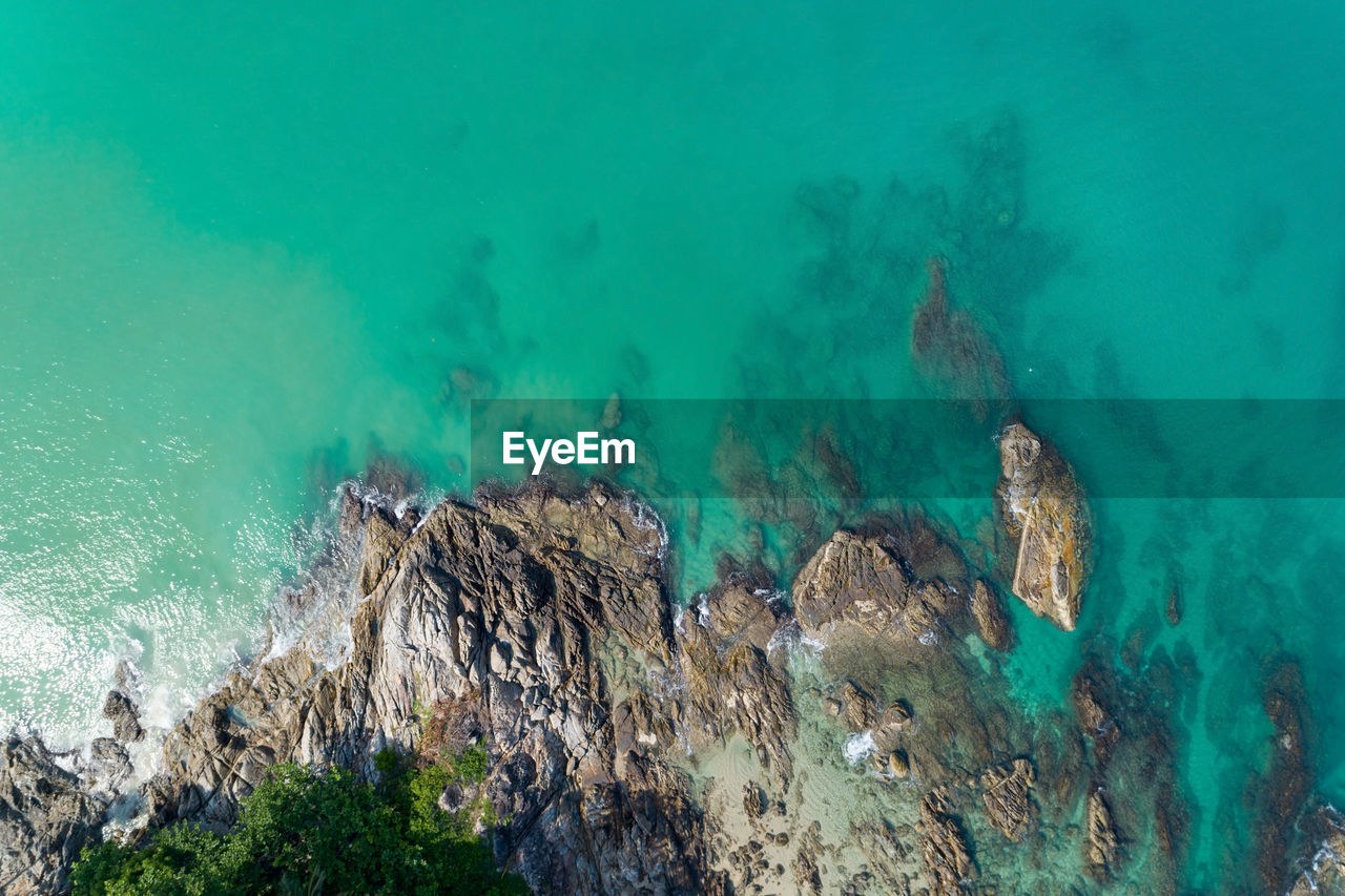 HIGH ANGLE VIEW OF ROCKS AND SEA