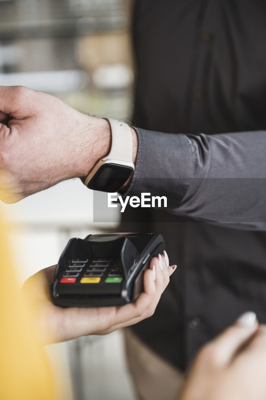 Businessman paying with smart watch on card reader machine