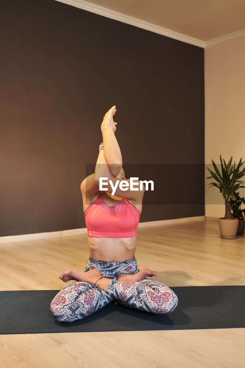 Young woman doing yoga on yoga mat in atmospheric yoga studio