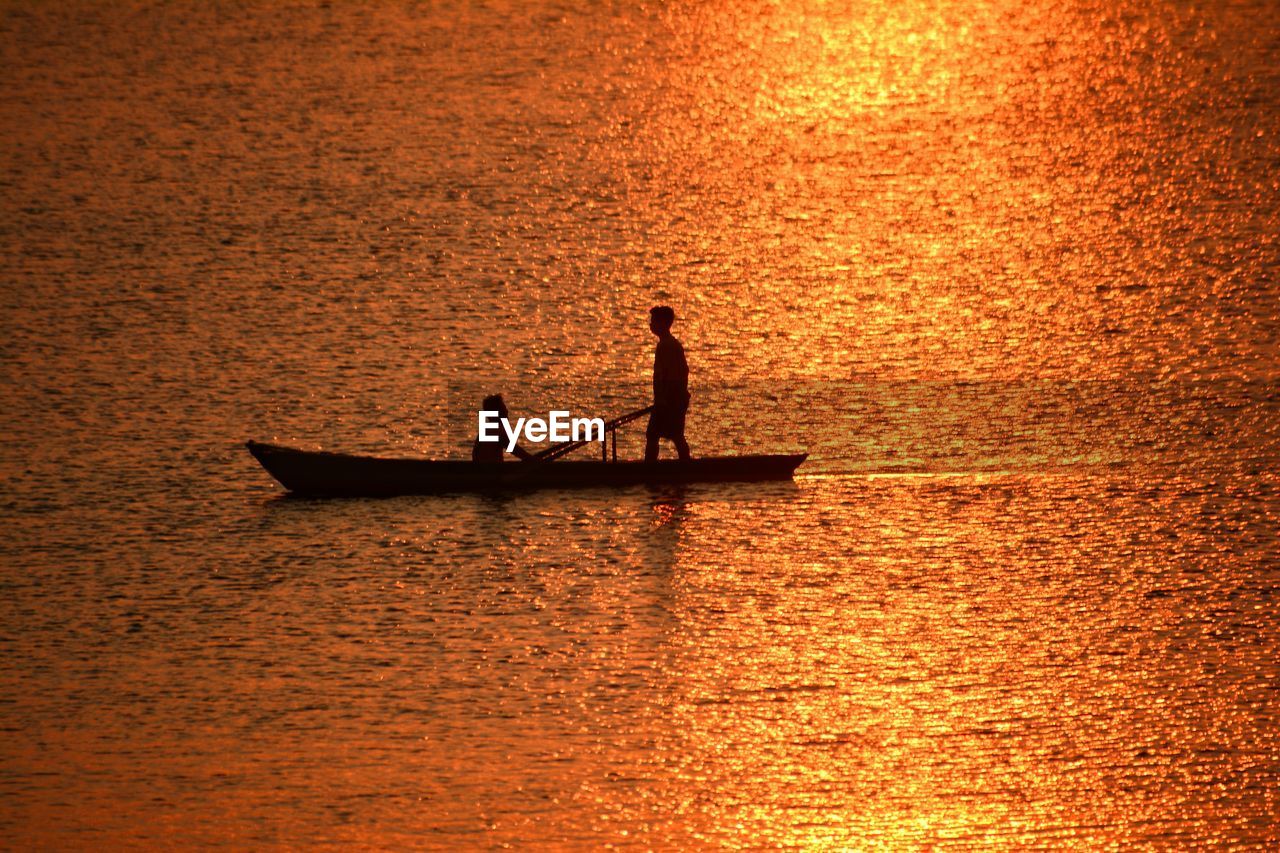 SILHOUETTE PEOPLE ON BOAT IN SEA DURING SUNSET