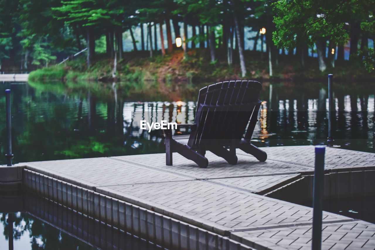 Empty chairs by lake in park