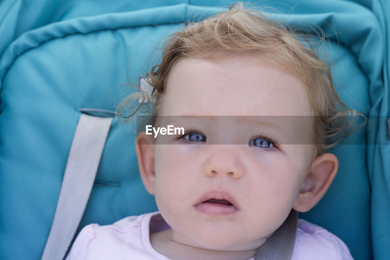 Close-up portrait of cute baby girl with blue eyes in stroller