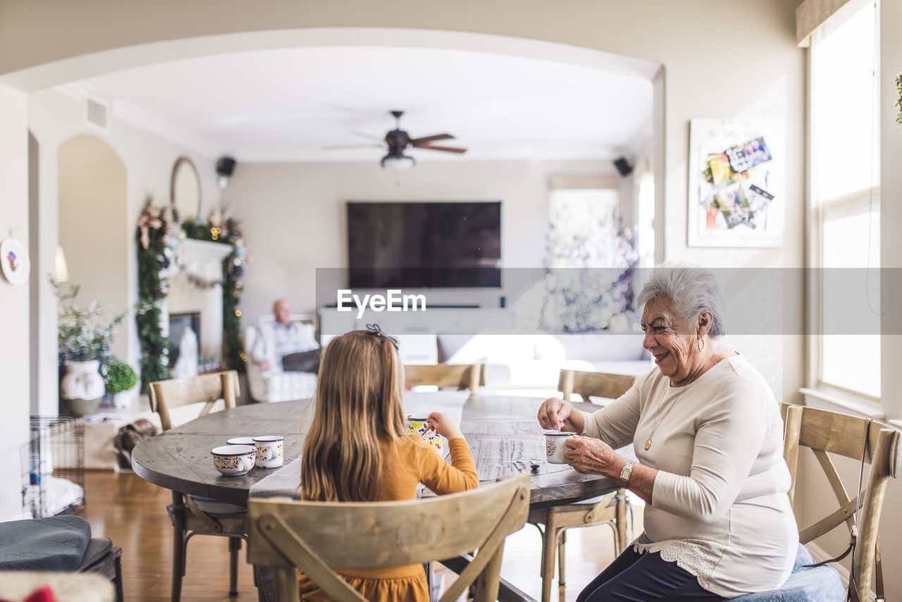 Multigenerational family playing with tea set at kitchen table