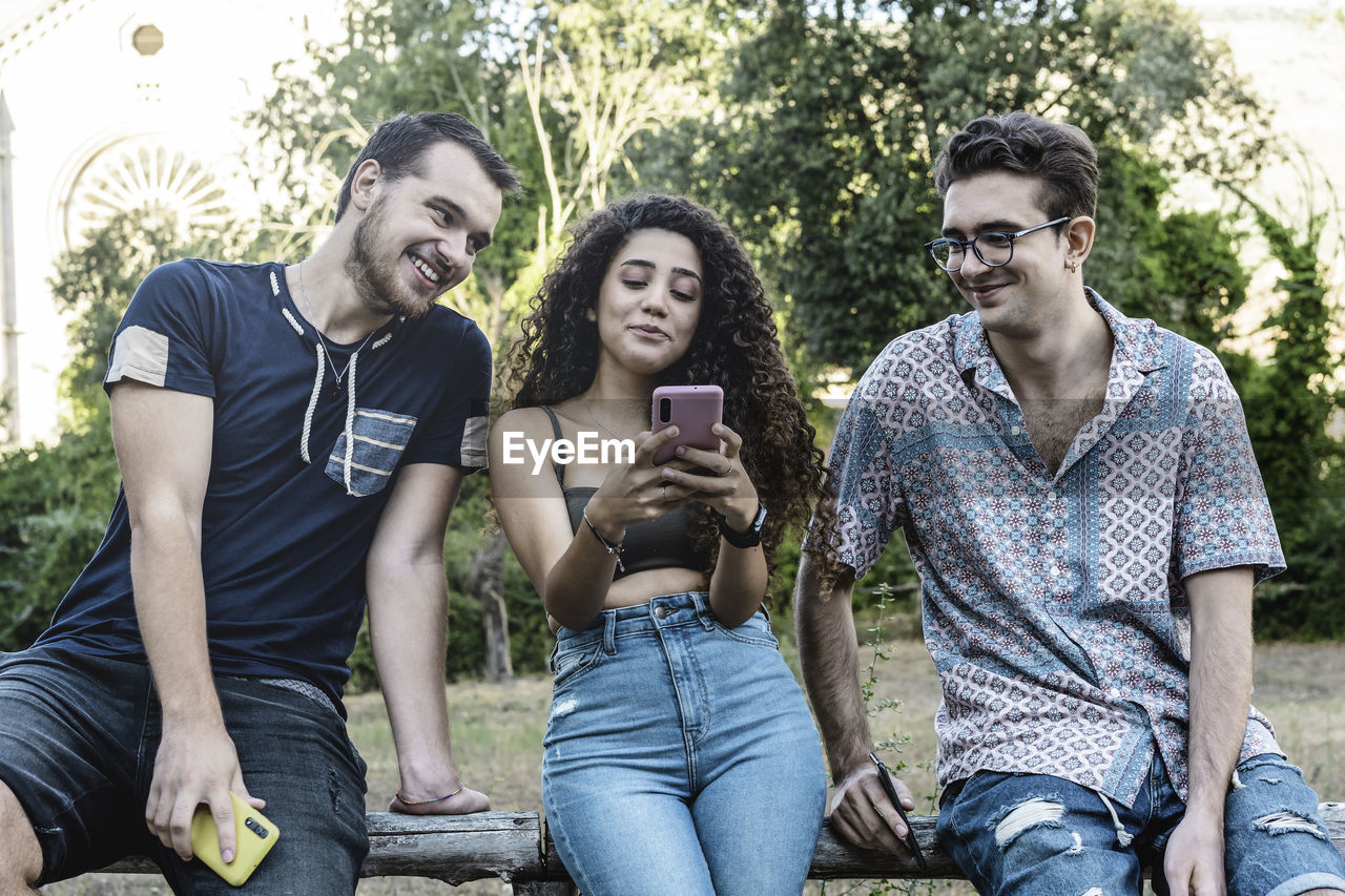 FULL LENGTH OF YOUNG MAN USING PHONE WHILE SITTING ON MOBILE