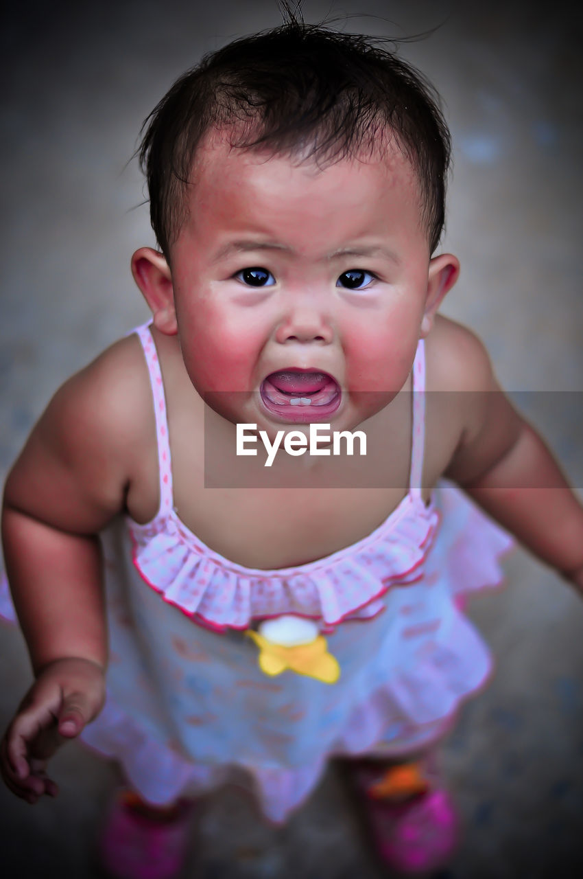 High angle portrait of cute baby girl crying while standing on road