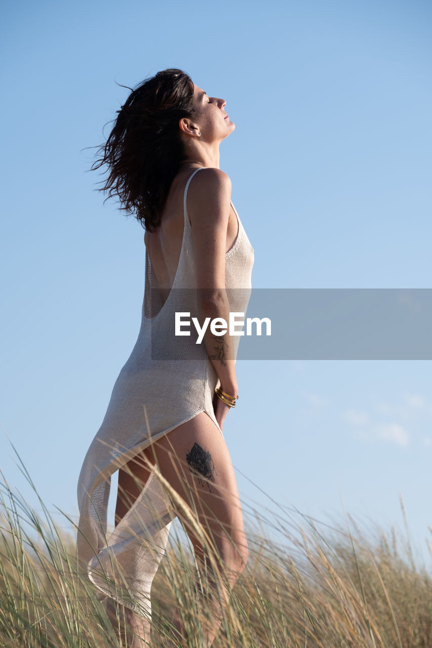 Young woman standing against sky