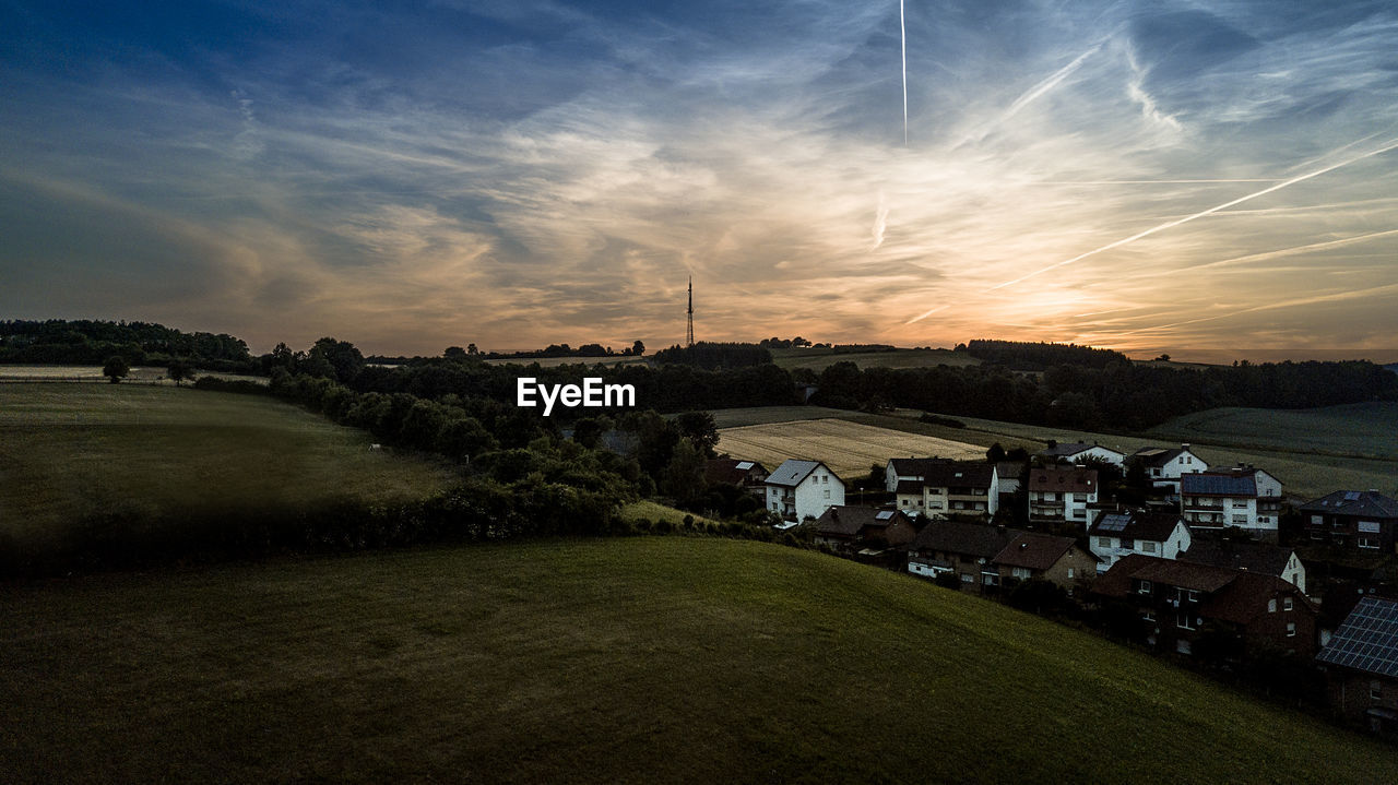 HOUSES ON FIELD AGAINST SKY