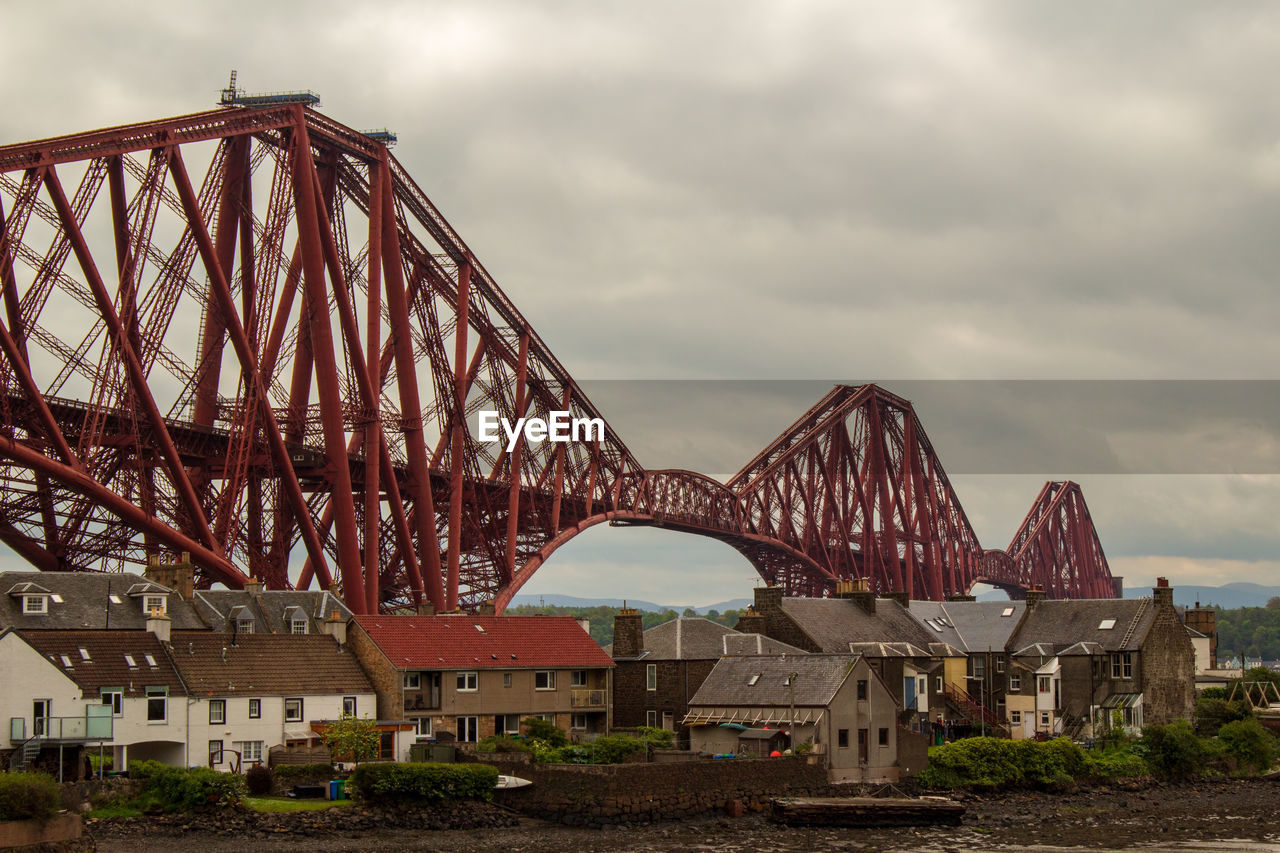 Forth bridge over river in city against sky