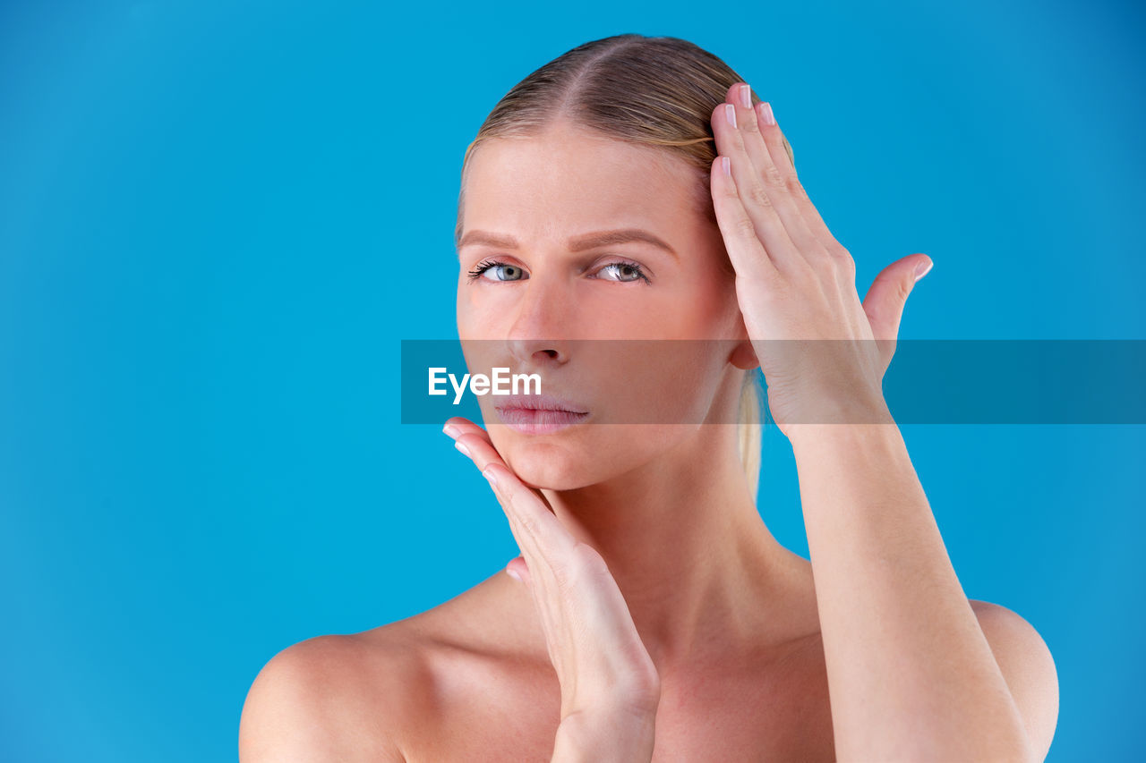 PORTRAIT OF A BEAUTIFUL YOUNG WOMAN OVER BLUE BACKGROUND