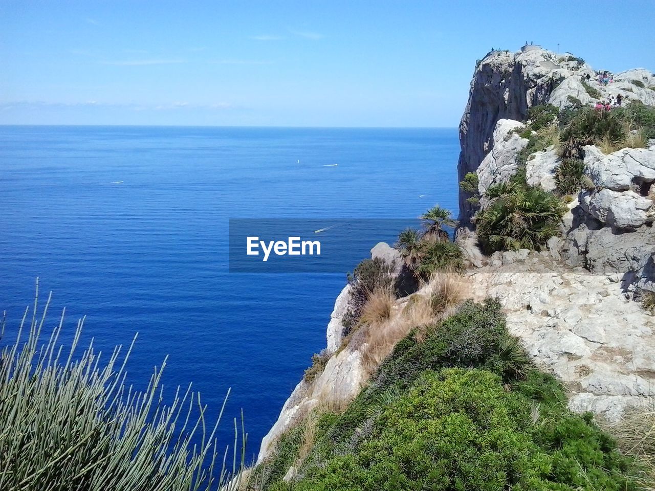Scenic view of cliff and blue sea against sky