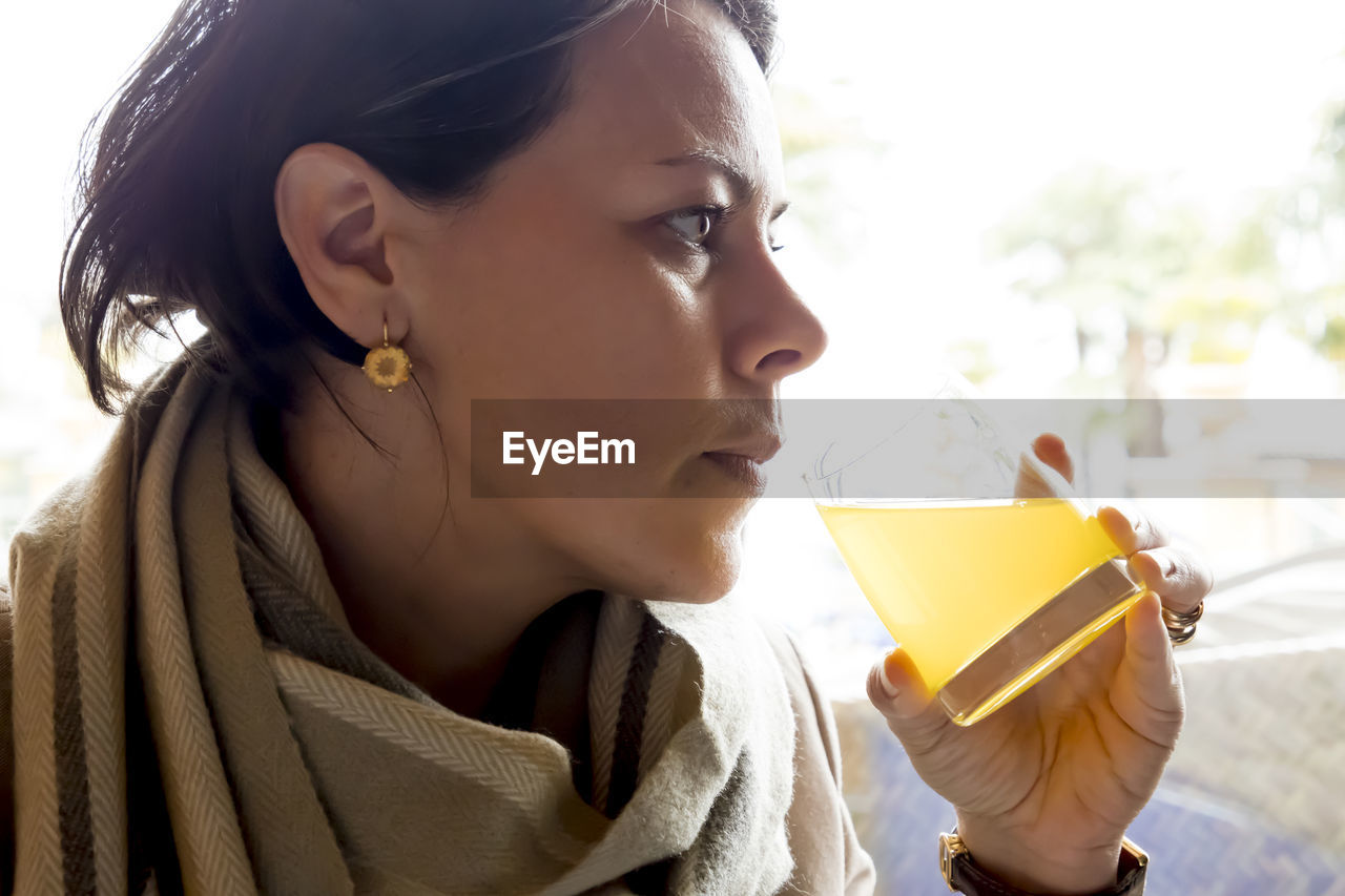 Close-up of thoughtful woman having drink in glass