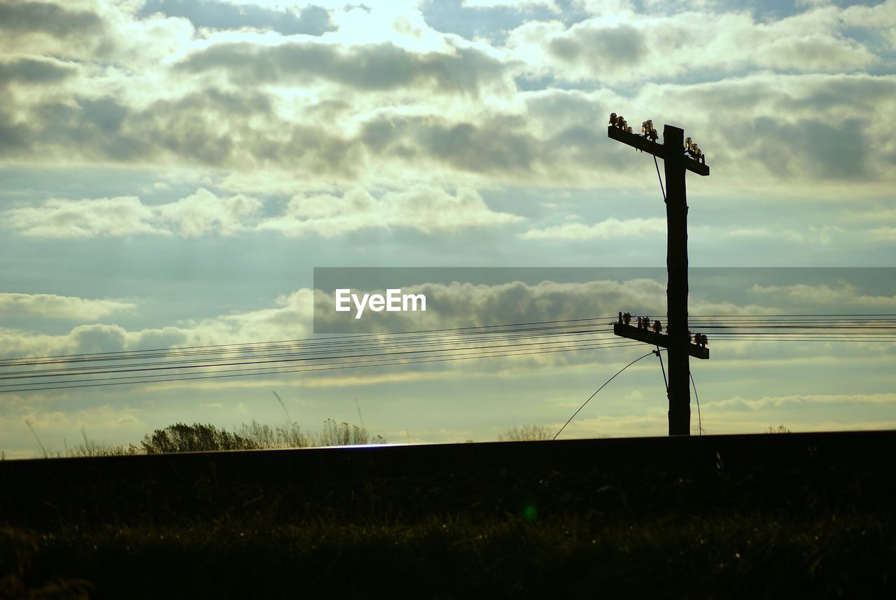 Silhouette electricity pylons against sky