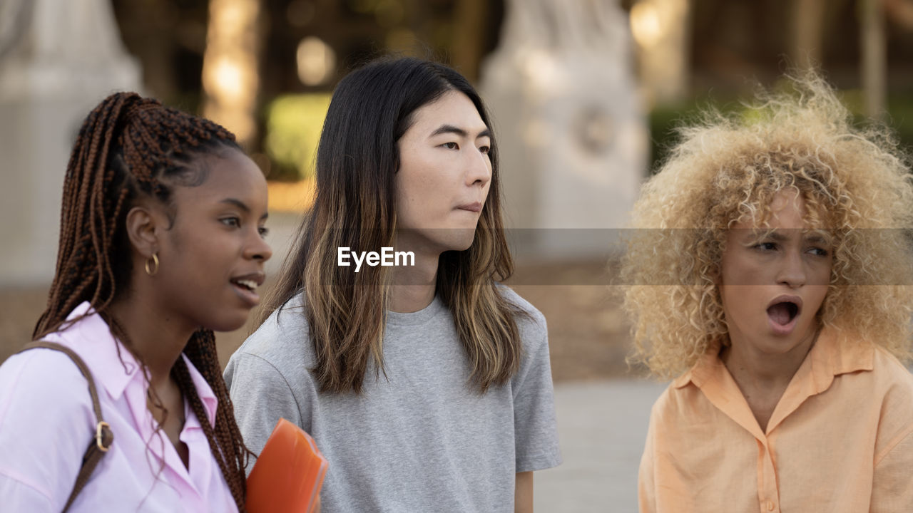 Multi ethnic students looking away with expression of surprise in the face standing on a campus