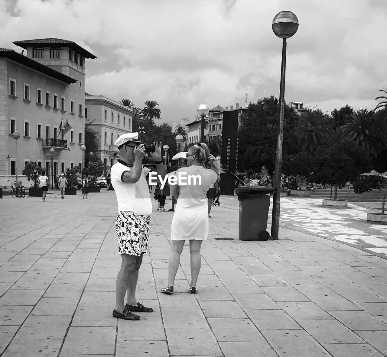 REAR VIEW OF PEOPLE STANDING ON STREET AGAINST SKY