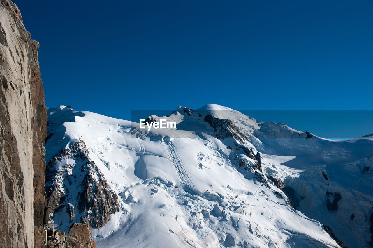 Scenic view of snowcapped mountains against clear blue sky