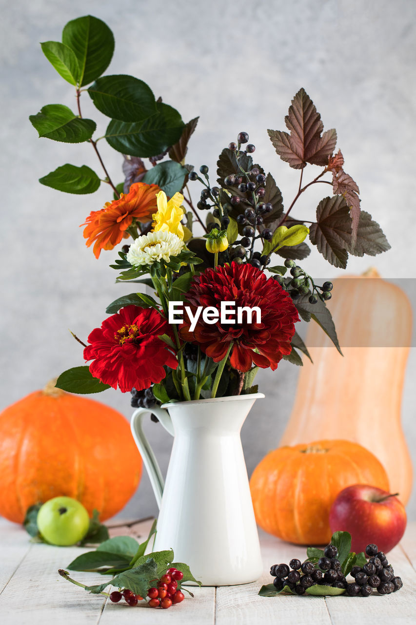 Elegant autumn bouquet with ripe apples and pumpkin on table. thanksgiving day