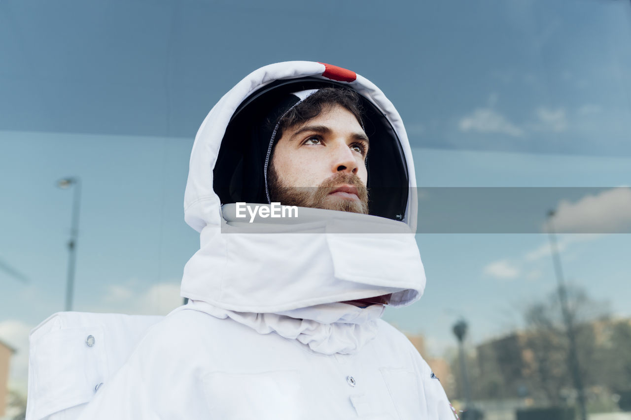 Thoughtful male astronaut in space suit looking away in city